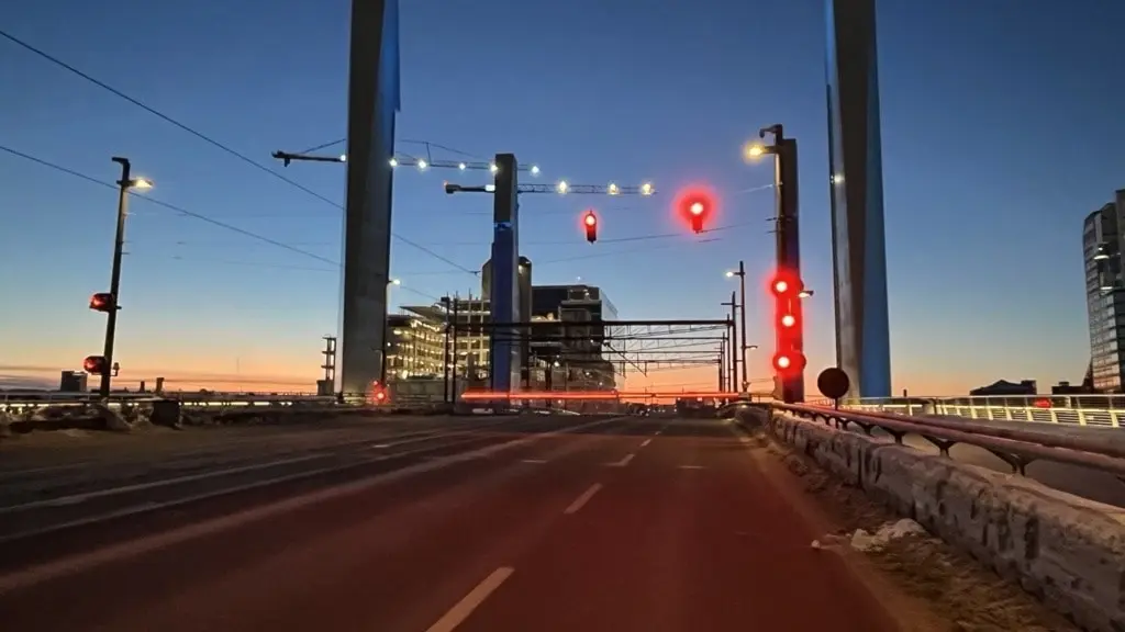 Hisingsbron i gryning den 11 januari 2025, med upplysta stolpar och trafikljus. En klar himmel och stadens siluett syns i bakgrunden. Vägmarkeringar och reflekterande ljus framhävs tydligt.