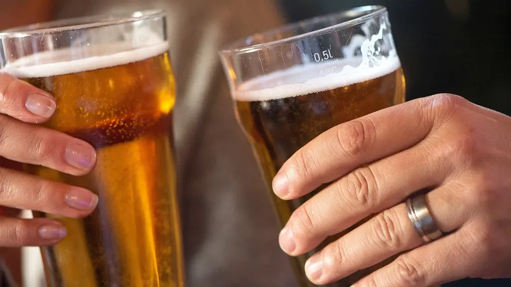 Två händer håller ölglas fyllda med gyllene öl under en skål på en pub. En ny undersökning visar att alkoholkonsumtionen ökar under sommaren. Bilden symboliserar socialt drickande.