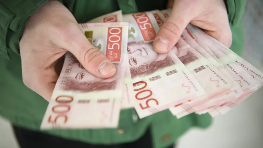 En person håller flera svenska 500-kronorssedlar i händerna. Sedlarna visas tydligt och bakgrunden är oskarp. 