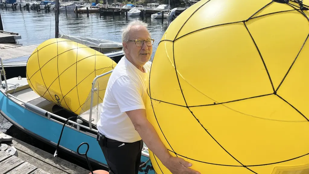 Lennart Johansson Ax står på brygga vid vattnet hanterar stor gul boj, med flera bojar i bakgrunden. Hamnmiljö och sjösäkerhet i fokus.