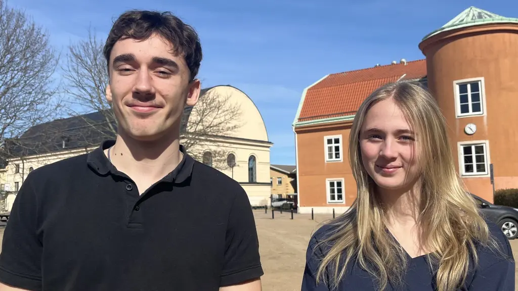 Elis och Sonja står på skolgården i solen och ler mot kameran 