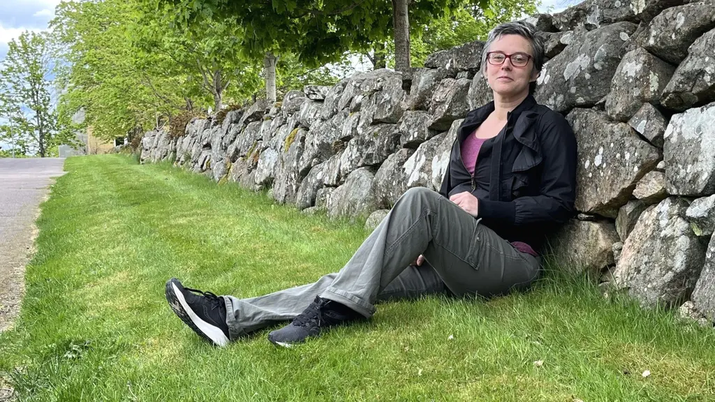 Pernilla Sandström från Ljungby som har ett barn med autism säger att det är en tuff väntan på hjälp. På bilder sitter hon på en gräsmatta lutad mot en lång stenmur.