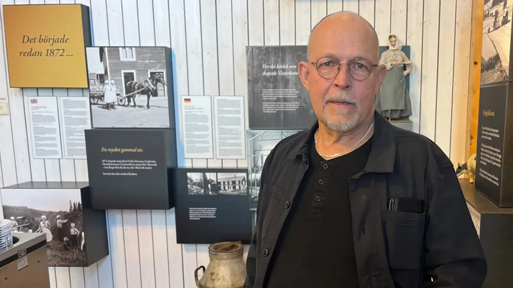 Stig står i rum med historisk utställning med bilder av ostar och texter på väggarna.