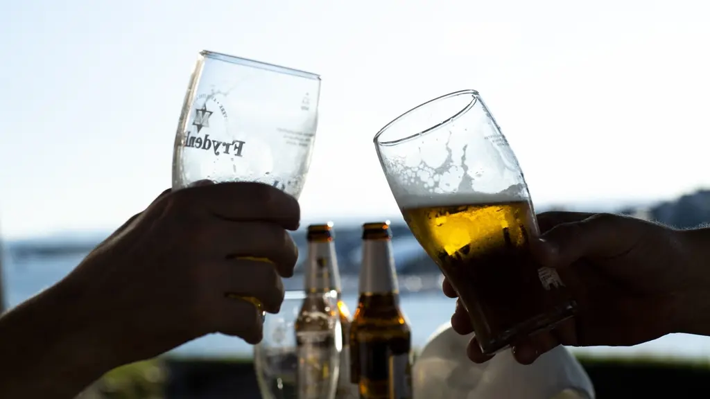 Två ölglas som hålls i av två personer, men man ser bara händerna.