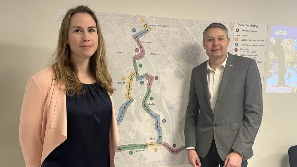En kvinna och en man framför en karta som visar spårvagnsbygget 2029.