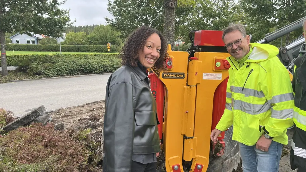 Felicia Johnson från Uppsala kommun och Örjan Ståhl, specialist inom trädvård, står utomhus vid en gul och röd maskin för trädhantering, omgivna av grönska.