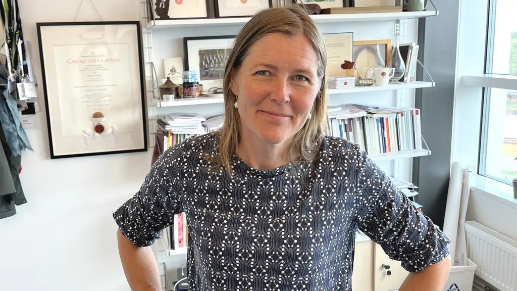 Carolina Wählby står i ett kontor med händerna på höfterna. Bakom henne syns en bokhylla med böcker, inramade diplom och fönster som släpper in dagsljus.