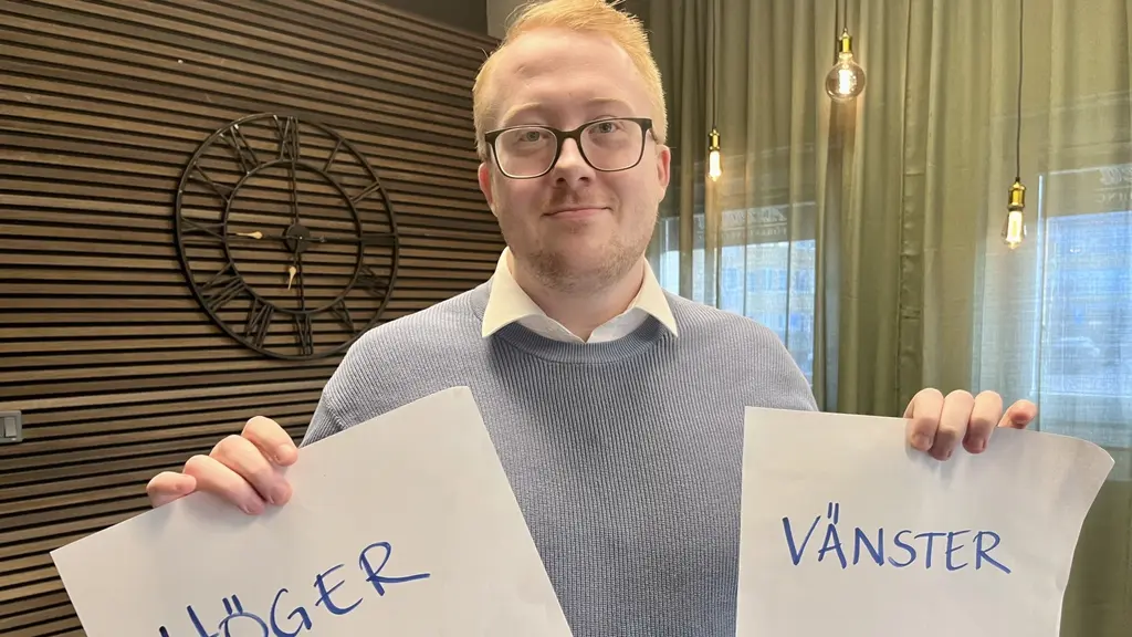 En trafiklärare håller upp två papper med orden 'Höger' och 'Vänster' skrivna. Bakgrunden visar ett rum med gröna gardiner och väggdekoration.