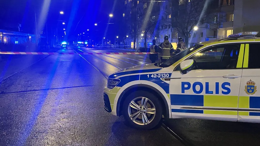 Polisbil och avspärrningar vid en nattlig skottlossning i Norrköping. Blåljus lyser upp gatan där flera poliser arbetar. Det grova våldet oroar och utreds av polisen.