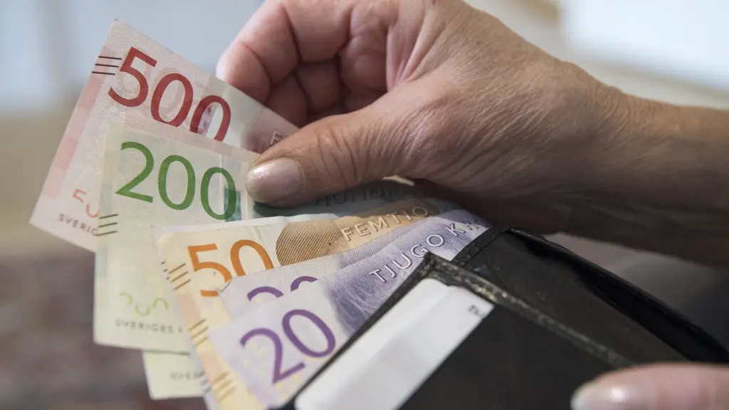 En pensionär håller en plånbok med svenska sedlar i olika valörer, inklusive 500, 200, 50 och 20 kronor. Bilden illustrerar pensionärsekonomi och privatekonomi.