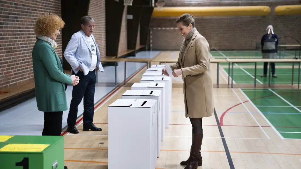 Kvinna i gymnastiksal lägger ett papper i en trälåda. 