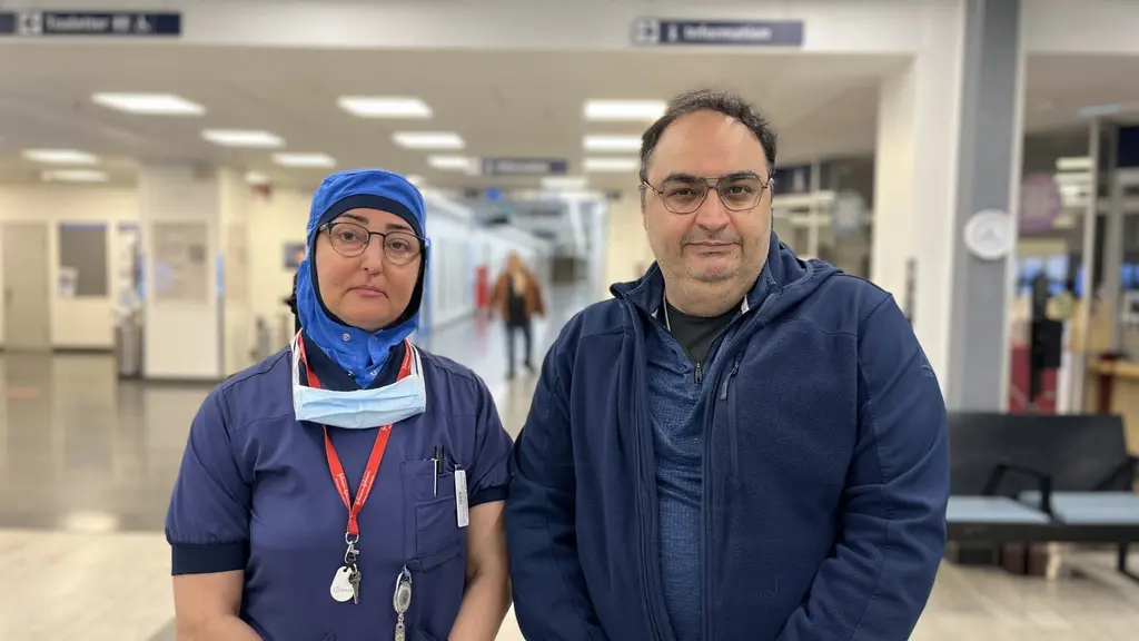 Zahra Kazemipour och Afshad Joubeh står i ett sjukhus med arbetskläder. 