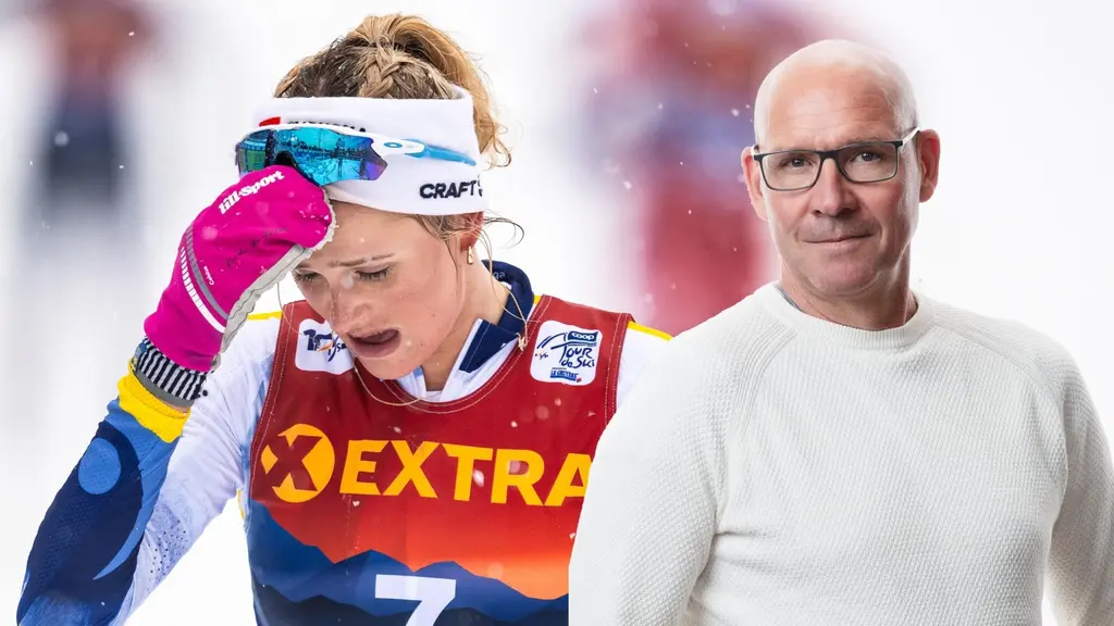 En person klädd i en färgglad sportdräkt med nummer 7 på bröstet står på en tävlingsbana. En annan person i vit tröja befinner sig i bakgrunden. Miljön är snöig och vinterlik.