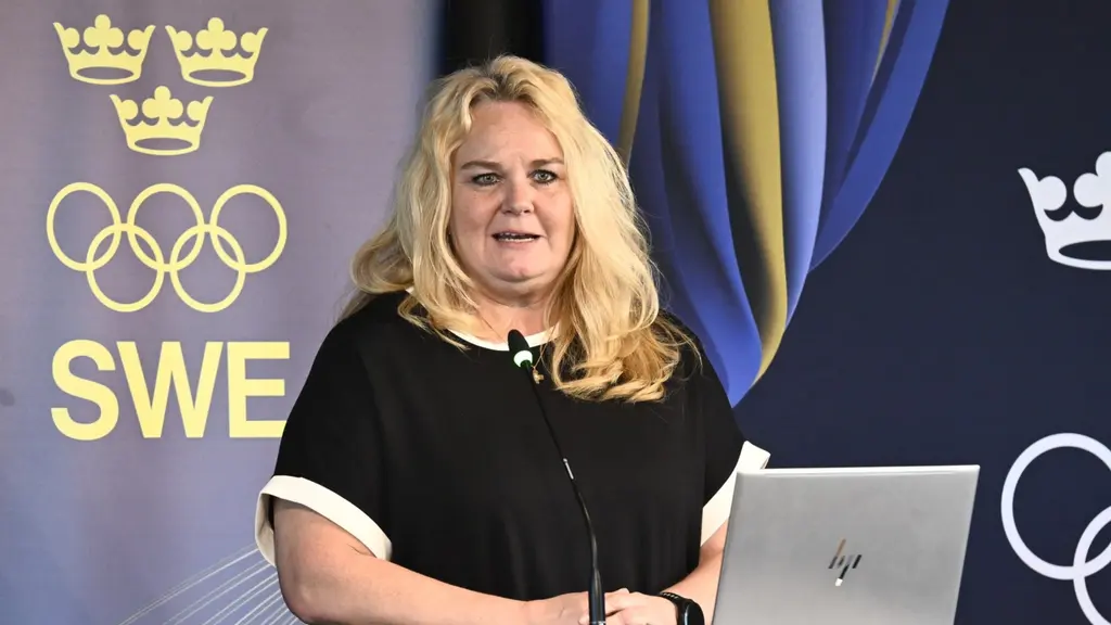 Generalsekreterare Åsa Edlund Jönsson talar vid Sveriges Olympiska Kommittés årsmöte i Stockholm, framför SOK:s och Sveriges olympiska symboler.