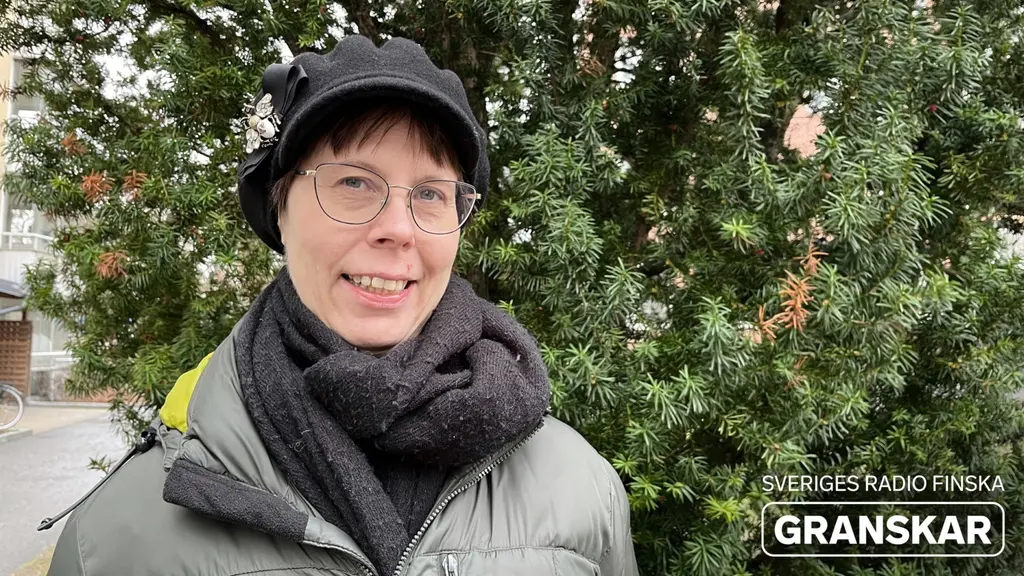 Reija Heikkilä står i varma ytterkläder framför en enbuske och ler. 