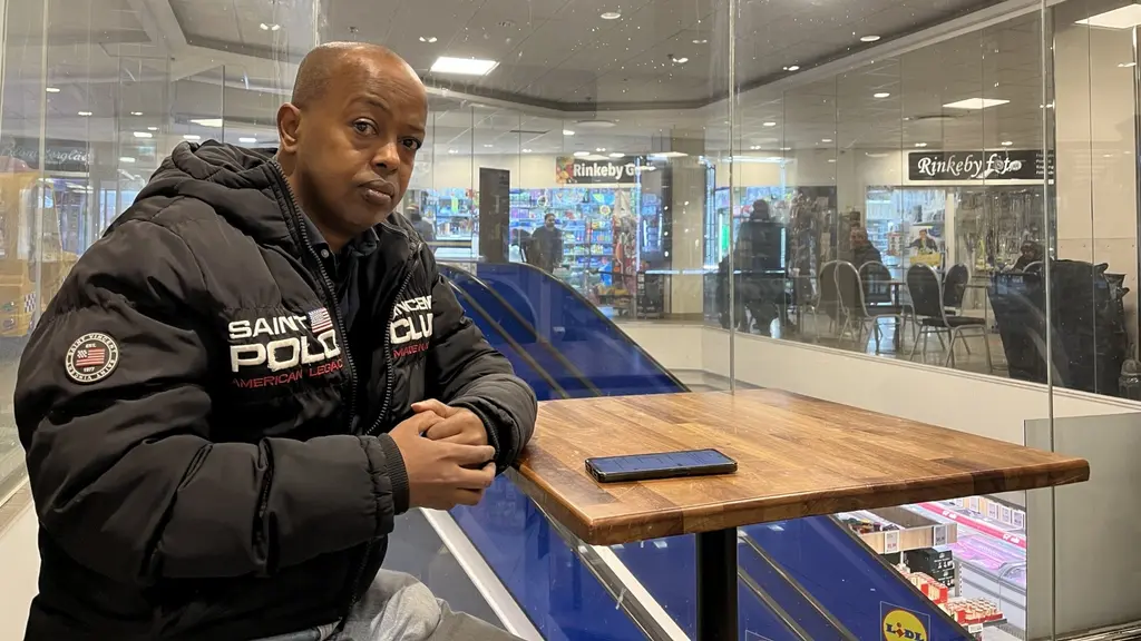 A man sitting by a café table in Rinkeby.