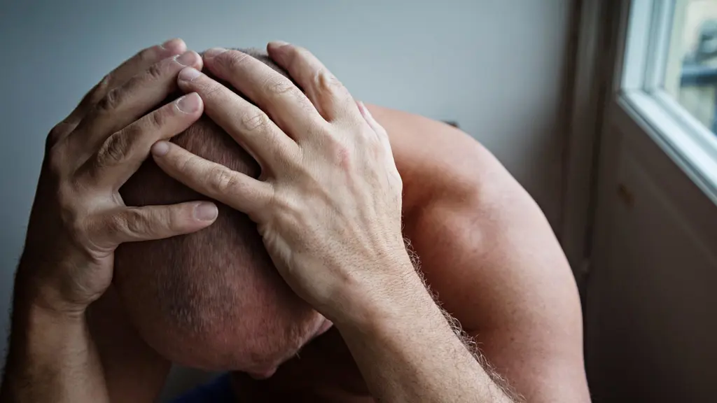 Man in a distressed state, covering his head with his hands.