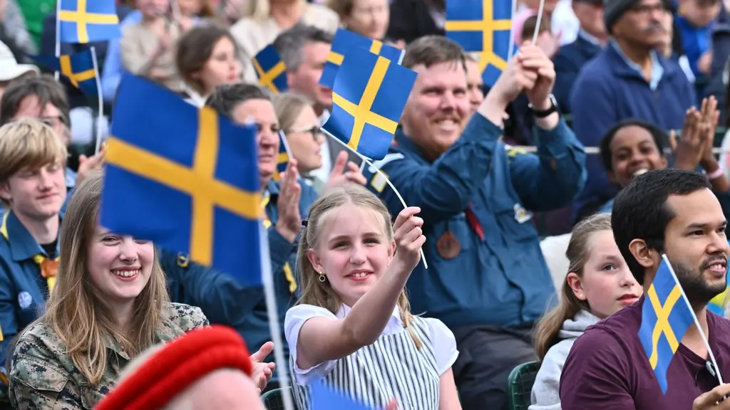 Smiling people holding flags during a national day celebration.