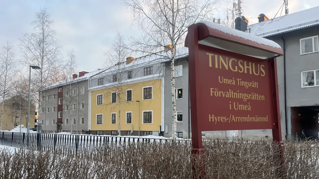 Skylt framför Tingshuset i Umeå med texten 'Umeå tingsrätt Förvaltningsrätten i Umeå Hyres- och arrendenämnden'. Bakom syns flerfamiljshus och snöklädda buskar.