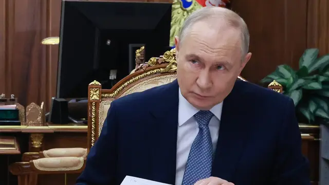 Rysslands president Vladimir Putin sitter vid ett skrivbord.