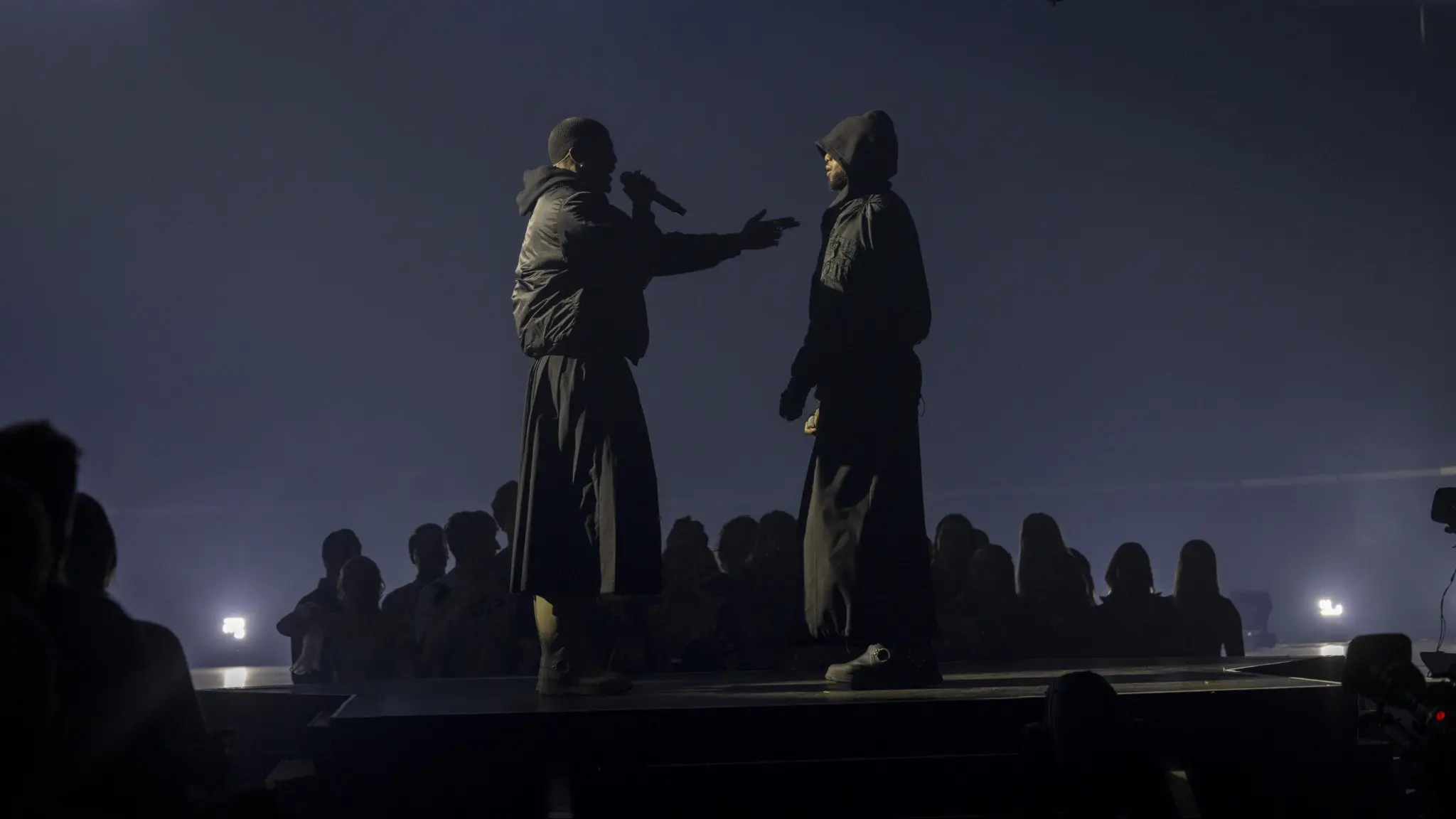 Två mörkklädda personer på en scen