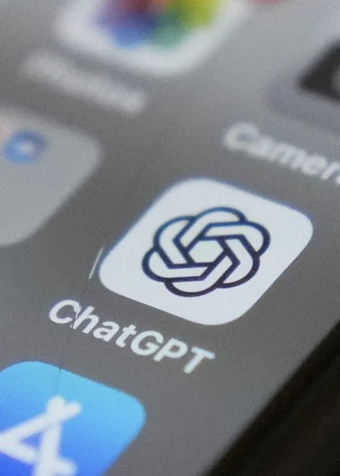 En närbild på en smartphone där appen ChatGPTs ikon syns tydligt på skärmen. Ikonen är placerad bland andra appar som kamera- och väderappar. Skärmen är mörk och detaljerna är skarpa.
