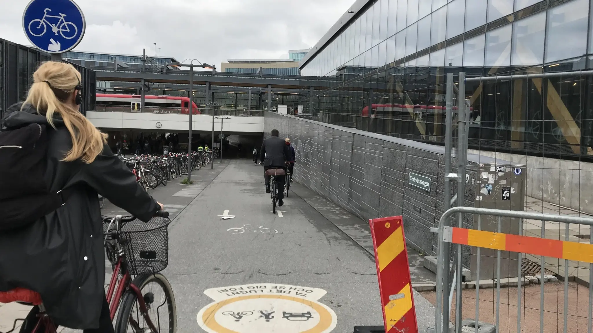 En kvinna kör in på en cykelbana vid Resecentrum i Uppsala. I förgrunden syns en avspärrning och i bakgrunden ett tåg.