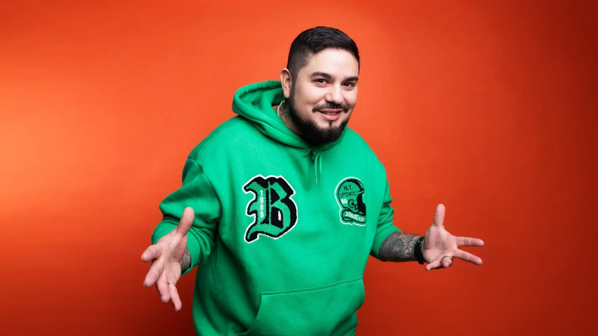 Programledaren Juan Havana i grön tröja framför röd bakgrund