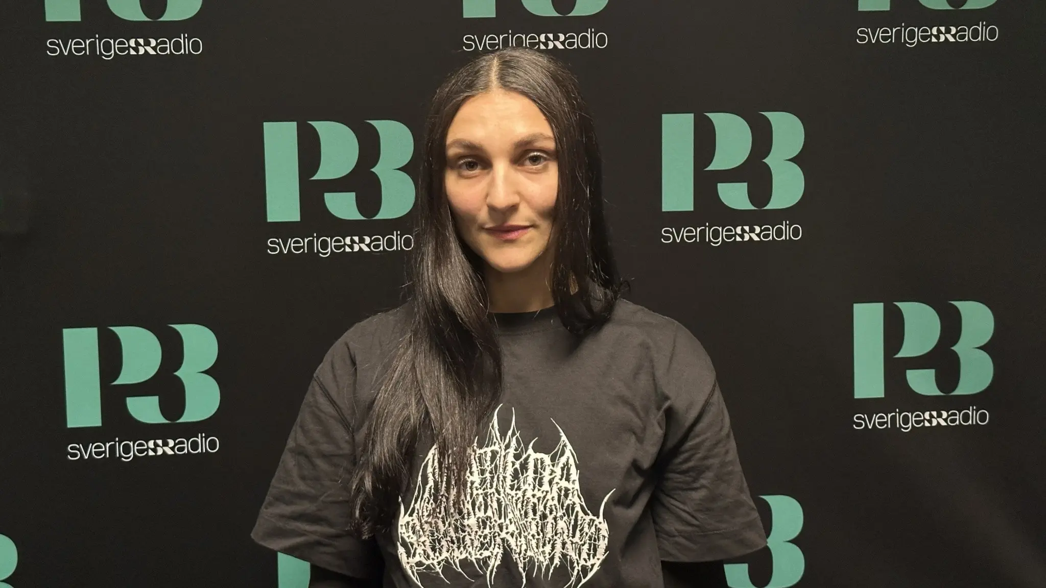 Artisten Nicole Sabouné fotograferad i en svart t-shirt framför en svart vägg.