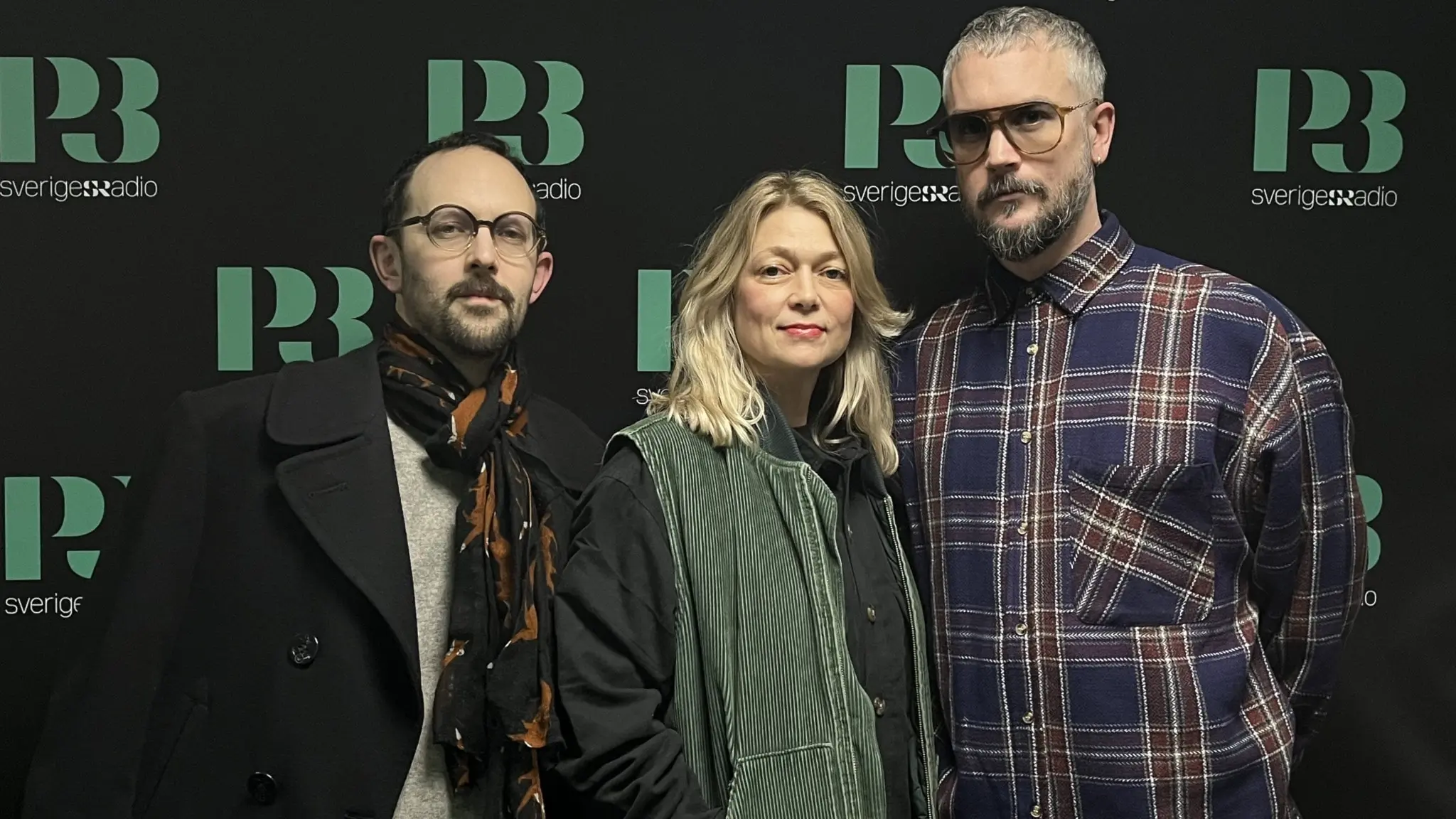 Anna Ahnlund, Daniel Ögren och Love Örsan från bandet Dina Ögon fotograferade i P3s studio framför en svart backdrop med P3s logga.