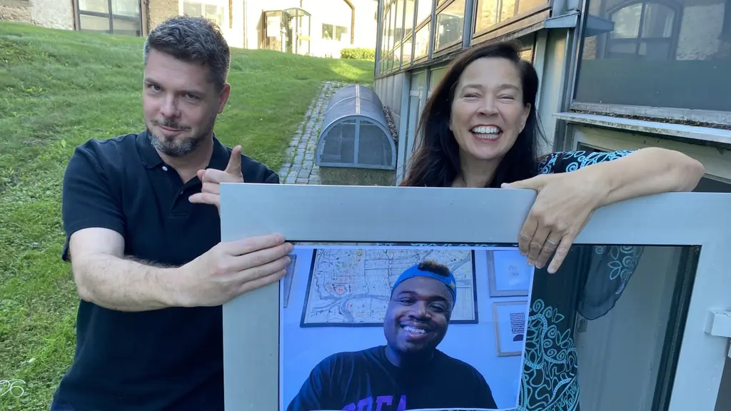 Stefan Ingvarsson och Marie Lundström håller ett utskrivet foto av Bryan Washington emellan sig. De står utomhus vid en öppen dörr i den glasade radiohusfasaden.