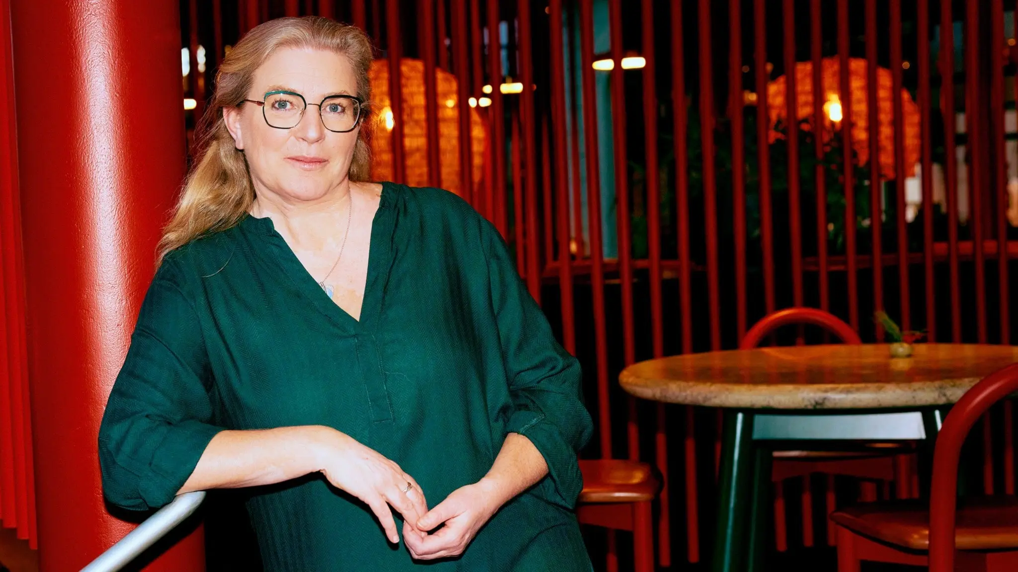 Klassisk morgons programledare Pernilla Eskilsdotter lutar sig mot en färgglad pelare och stödjer sin ena arm mot en ledstång.