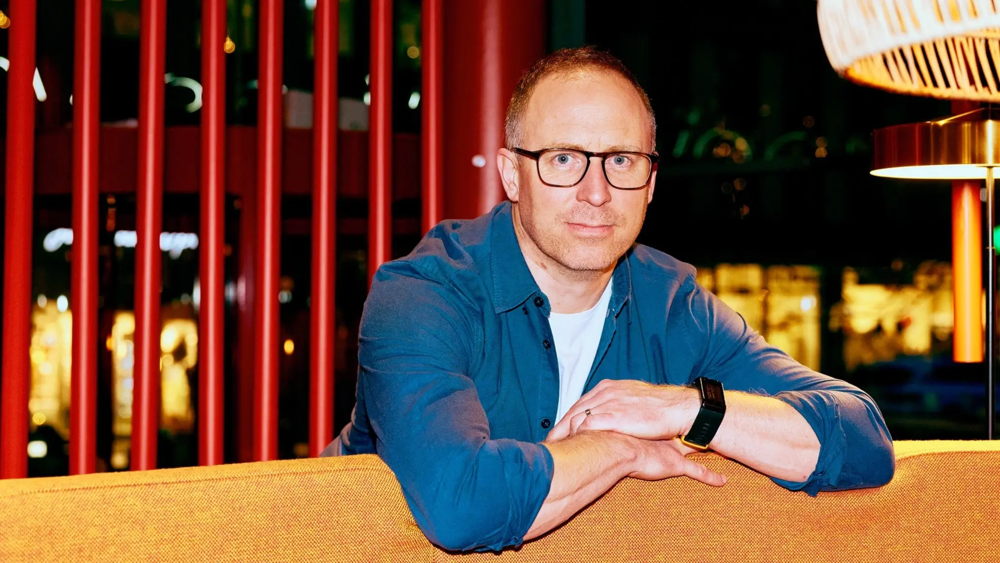 Klassisk morgons programledare Martin Ekeholm hänger på sina armar över ryggen på en färgglad soffa