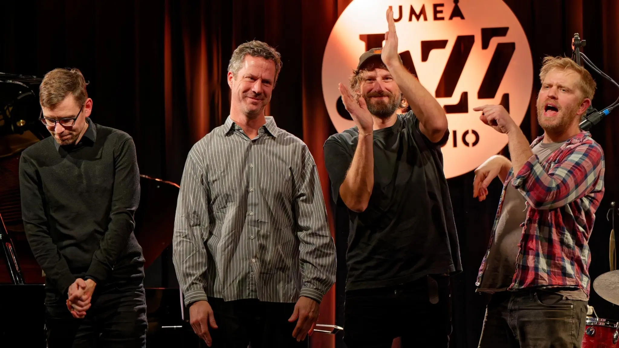 Fyra män står på en scen med Umeå Jazzstudios logotyp i bakgrunden. Från vänster Jonas Östholm, Martin Höper, Andreas Hourdakis och Jon Fält.