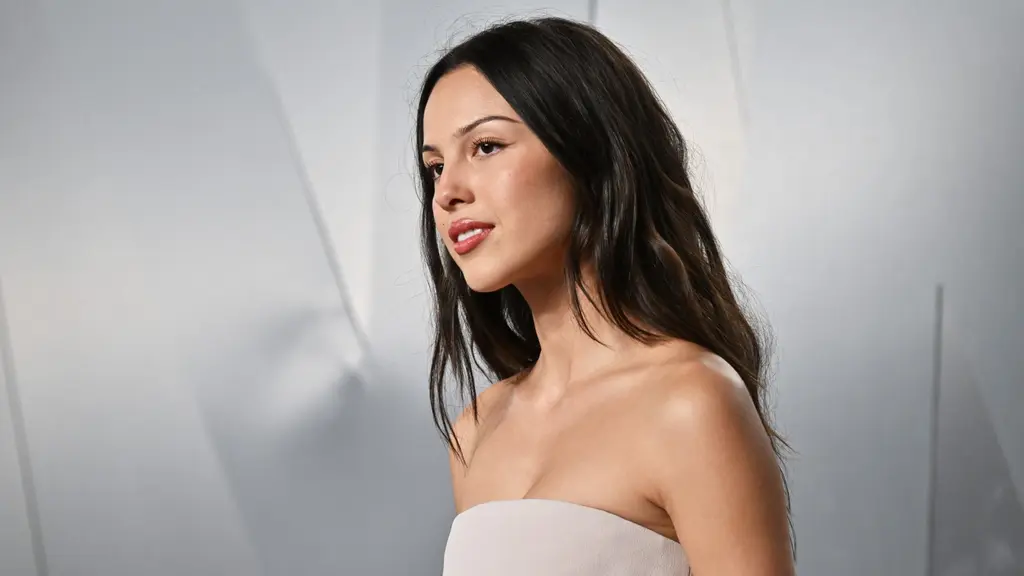 Olivia Rodrigo på Vanity Fair Oscar Party i Los Angeles, i axelbandslös ljus klänning mot grå fond på röda mattan.