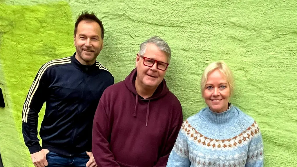 Mitt emellan Per och Annika i Da Buzz står Micke Cederberg. Han bär glasögon. Annika har en stickad långärmad tröja med krage och Micke har en hoodtröja och Per har en träningsoverallsjacka.