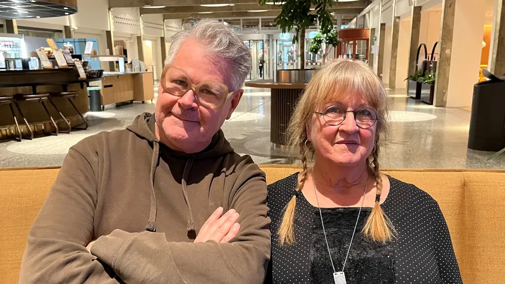 Micke Cederberg sitter till vänster med armarna i kors. Han bär glasögon. Jämte honom sitter Maj-Britt Niklasson. Micke bär glasögon. Maj-Britt har lugg och flätor på varsin sida. Hon har ett smycke i en halskedja. 