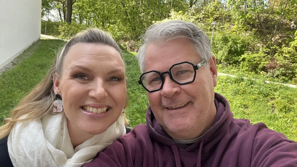 Sanna Nielsen och Micke Cederberg ler mot kameran. Sanna har långt hår och allt bakåtslickat. Micke bär glasögon. man ser utomhusgrönska bakom dem.