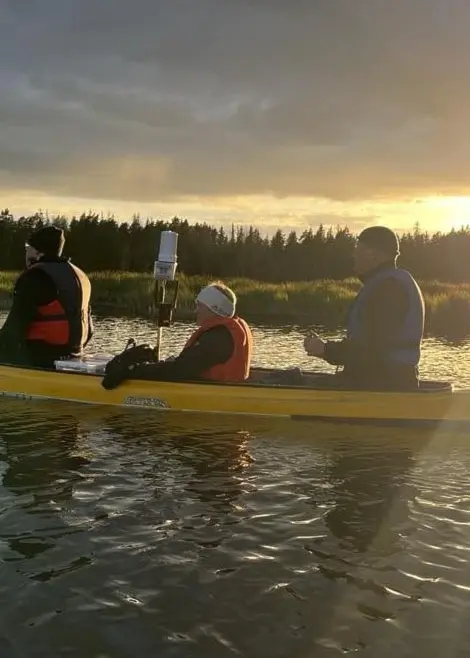 tre personer i kanot i kvällsljud