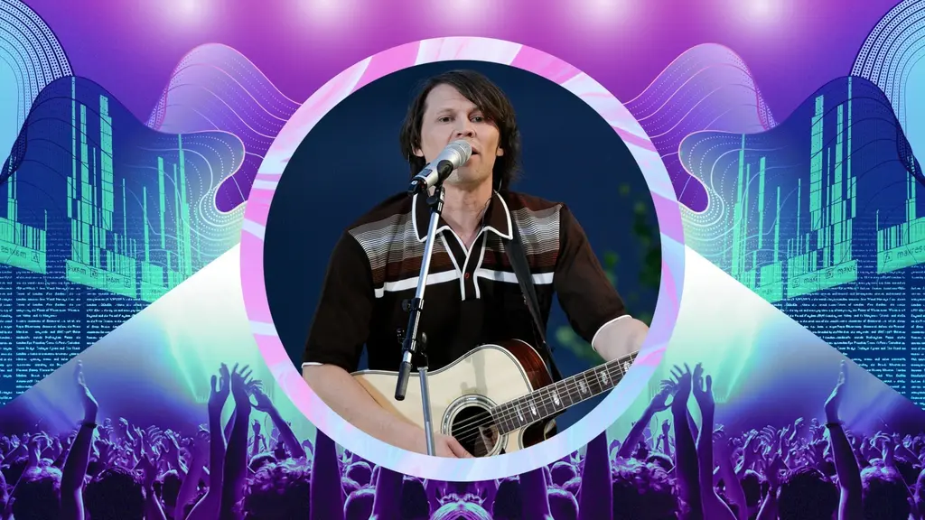 Jakob Hellman, klädd i brun skjorta, står på scen och sjunger och spelar gitarr.