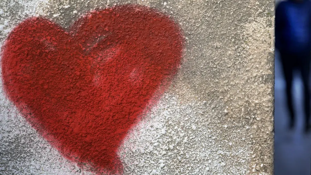 En rött stort hjärta målat med graffiti på en grå husvägg