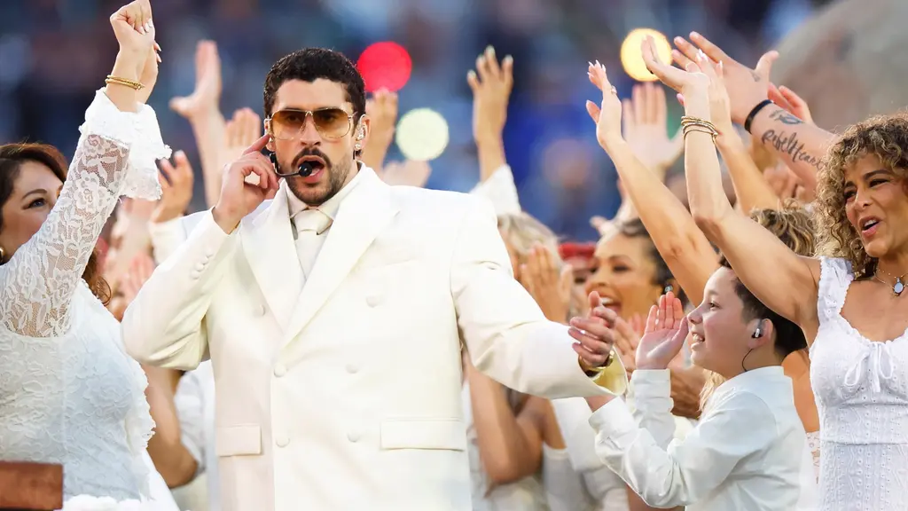 Artisten Bad Bunny klädd i vit kostym uppträder under Super Bowl 60:s halvtidsshow. Personen omges av dansare i vita kläder som höjer armarna i luften.