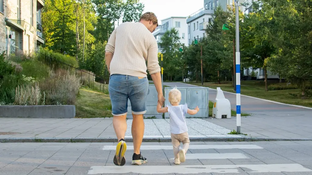 En pappa leder sin dotter över ett övergångsställe. 
