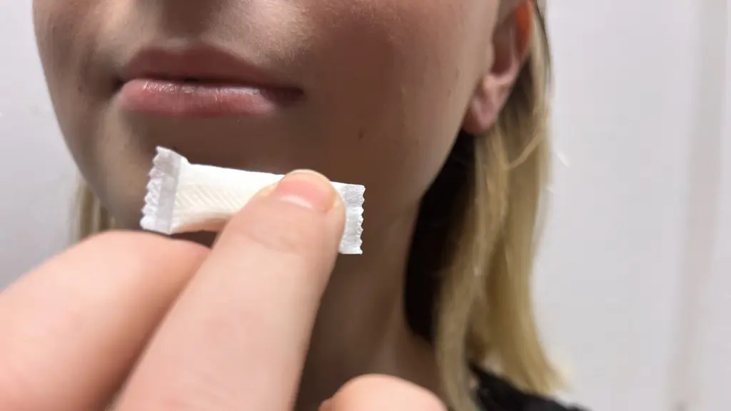 En tjej håller i en prilla vitt snus framför munnen. 