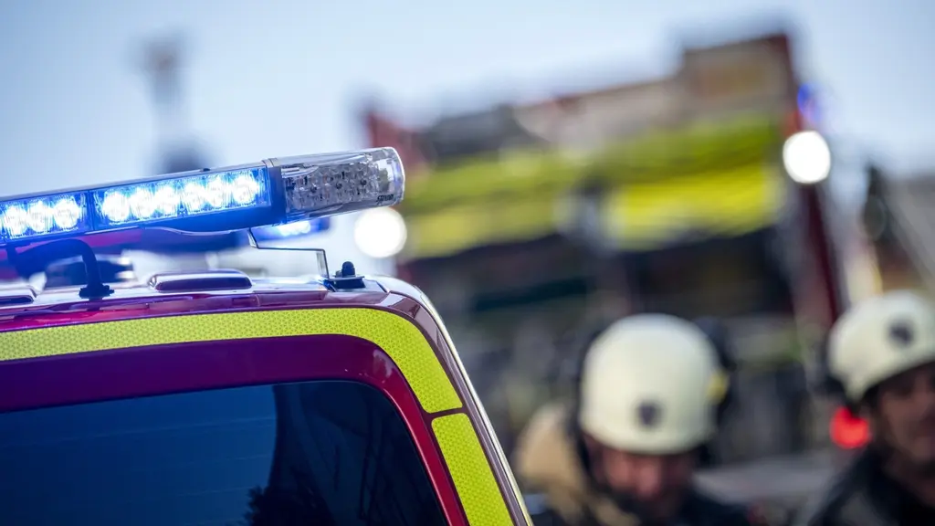 Räddningstjänstens fordon med blinkande blåljus vid en mindre brand på Norra Fäladen i Lund. Brandmän i hjälmar syns i bakgrunden nära brandbilen.