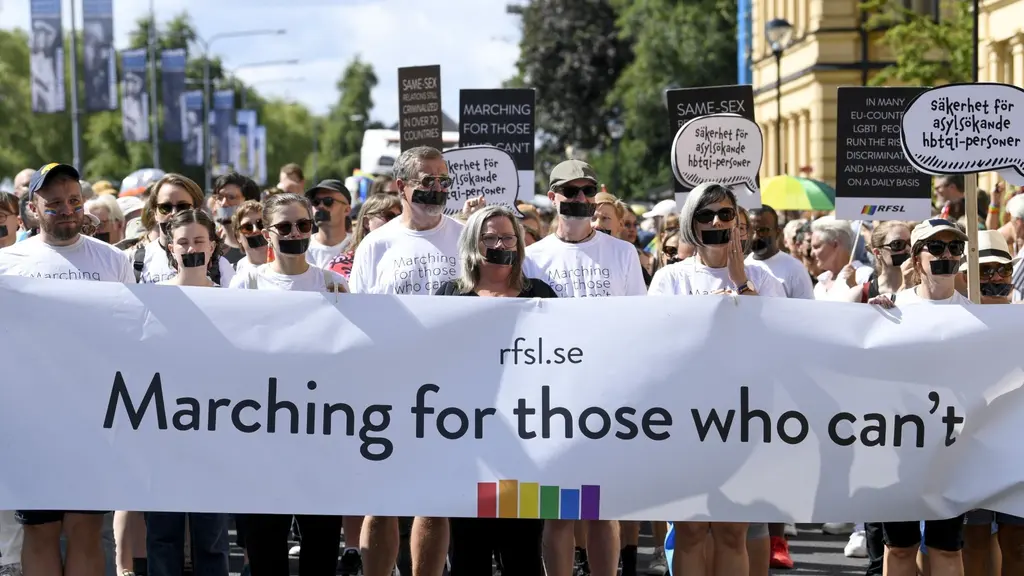 Personer med en tejpbit över munnen, hållandes banderollen: "Marching for those who can't"