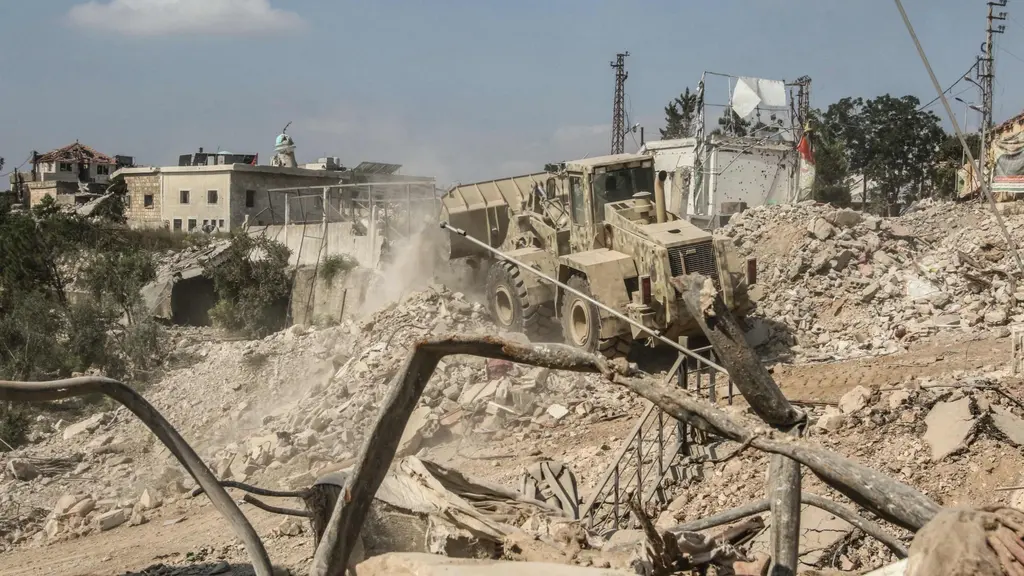 Libanesiskt arméfordon röjer rasmassor i Zawtar al-Gharbiyah i södra Libanon efter israeliska militäroperationer, omgivet av förstörda byggnader och damm.