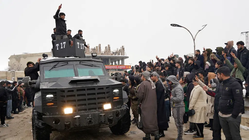 Ett militärfordon från de kurdiskledda Syriska demokratiska styrkorna (SDF) omringas av en folkmassa i staden Ain al-Arab, också känd som Kobane. Människor vinkar och samlas runt fordonet.