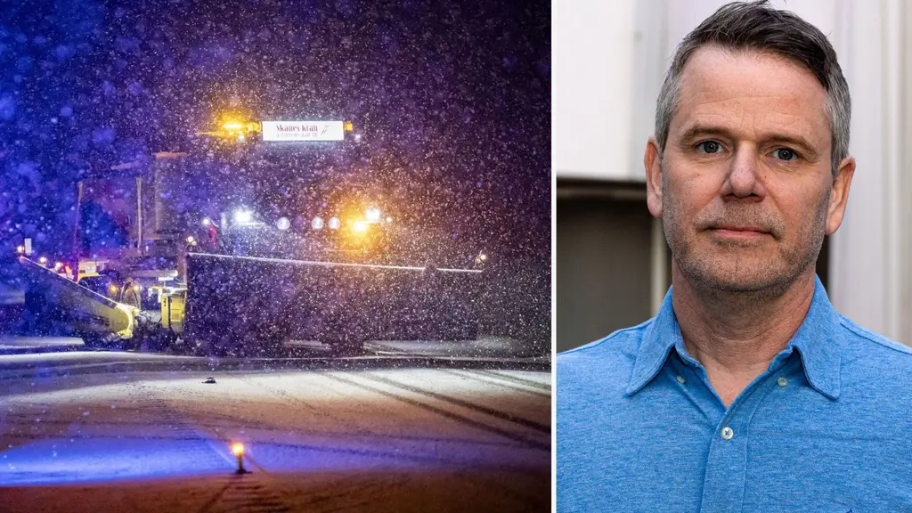 Snöfall täcker en flygplatsbana under kvällstid med upplysta markeringar. En blå skjorta syns på en person som är beskuren och oidentifierbar. Fokus ligger på vintervädret och flygplatsmiljön.