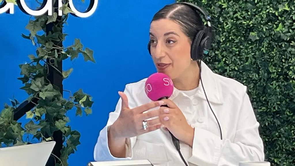 Liberalernas partiledare Simona Mohamsson i Almedalen, sittande i radiostudio med hörlurar och mikrofon. Framför henne syns mixerbord, med grönska och blå bakgrund i bild.